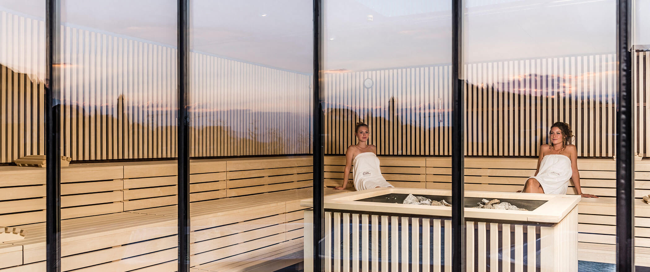 Due donne siedono nella sauna a infusione e guardano fuori - Vitalhotel Erica