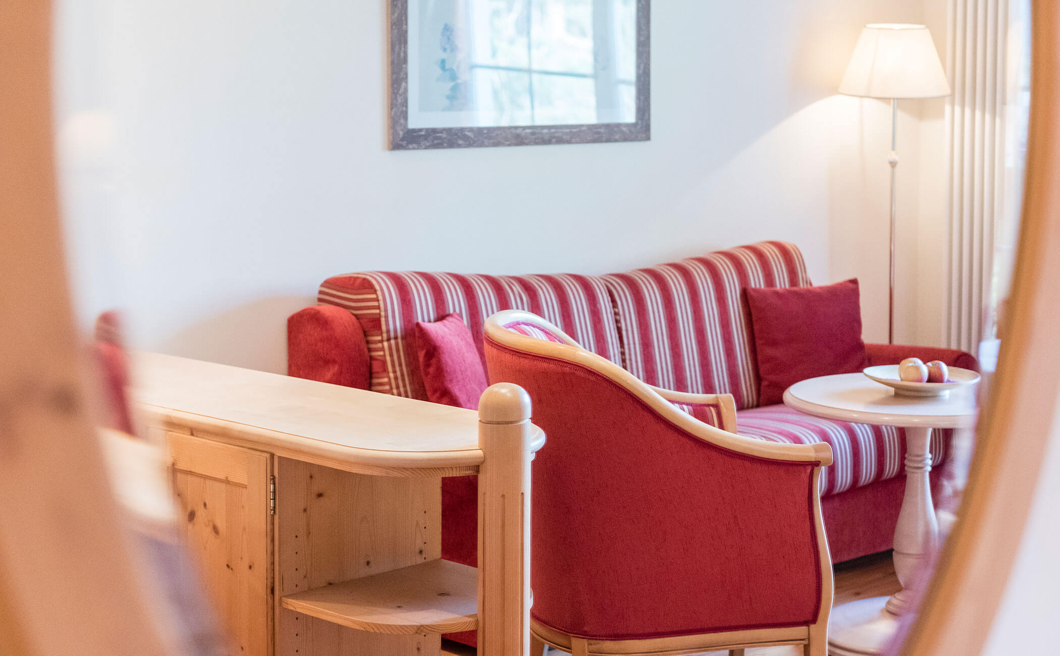 Divano rosso con strisce dorate nella zona giorno della suite familiare - Vitalhotel Erica