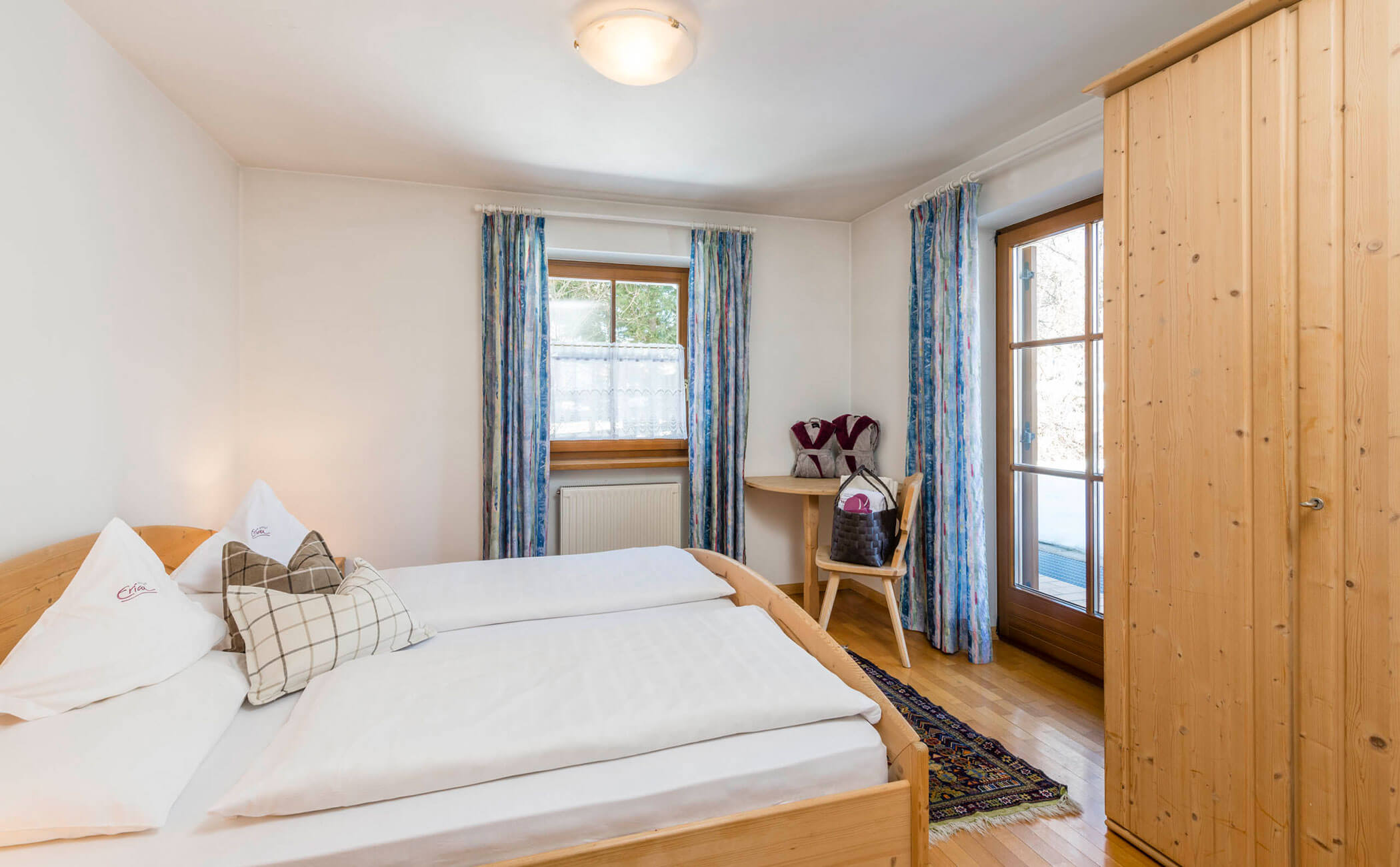 Camera da letto con letto matrimoniale e tende blu nell'appartamento vacanze - Vitalhotel Erica