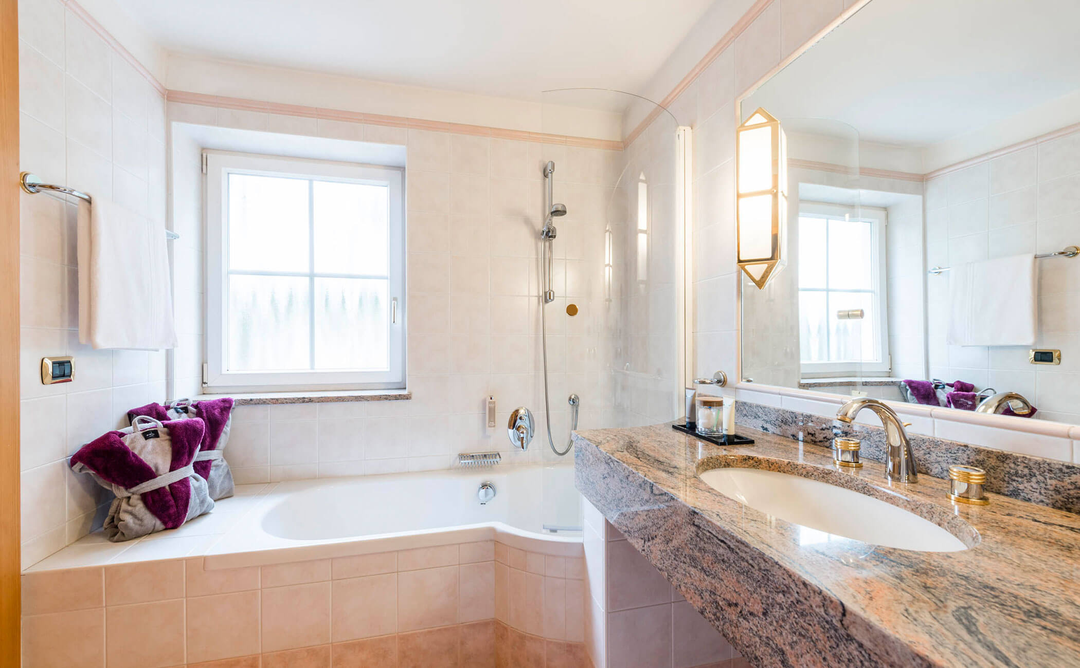 Bagno con lavabo con specchio e vasca nella junior suite Rosengarten Residence - Vitalhotel Erica