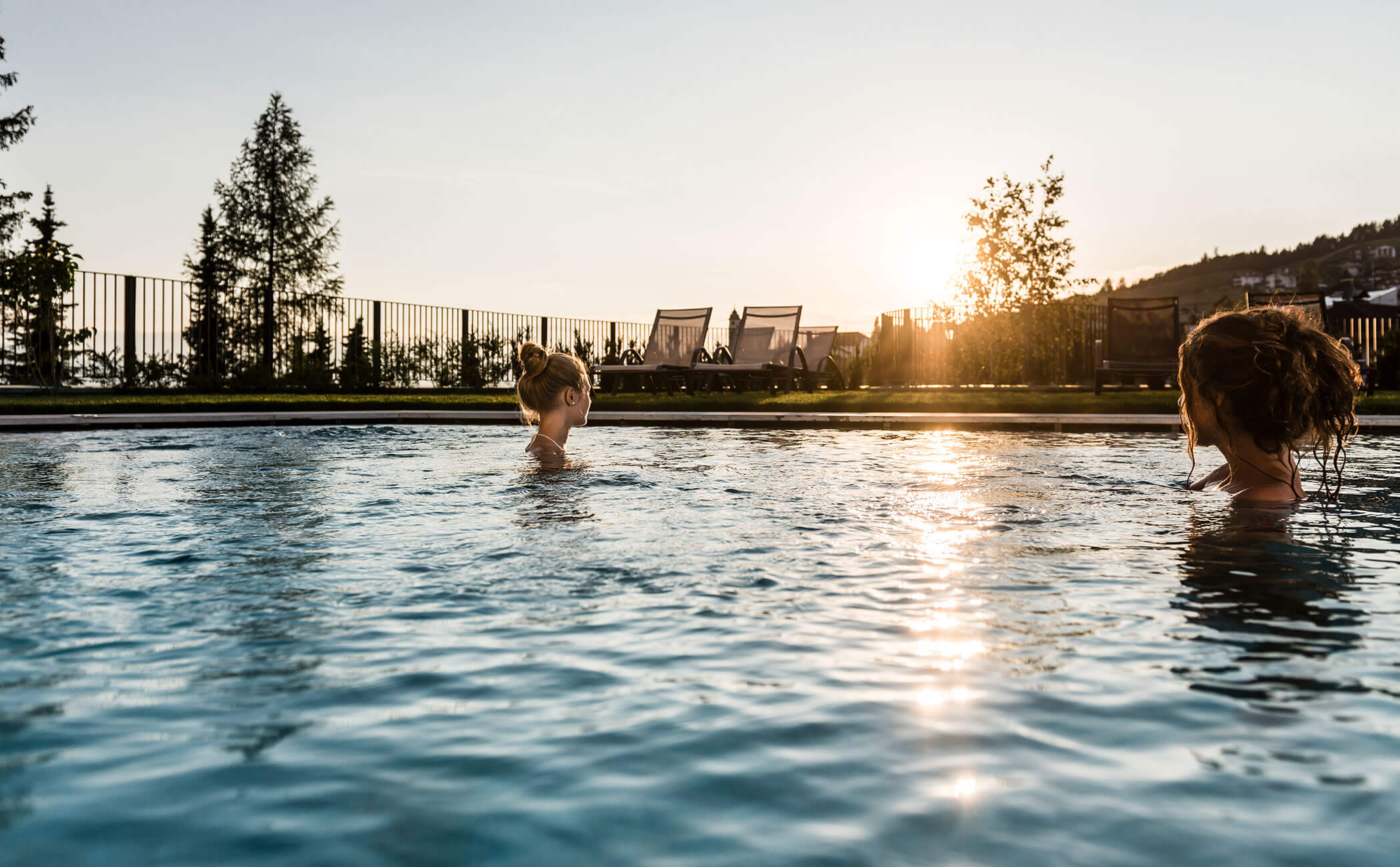 Two women in the outdoor pool as the sun sets - Vitalhotel Erica