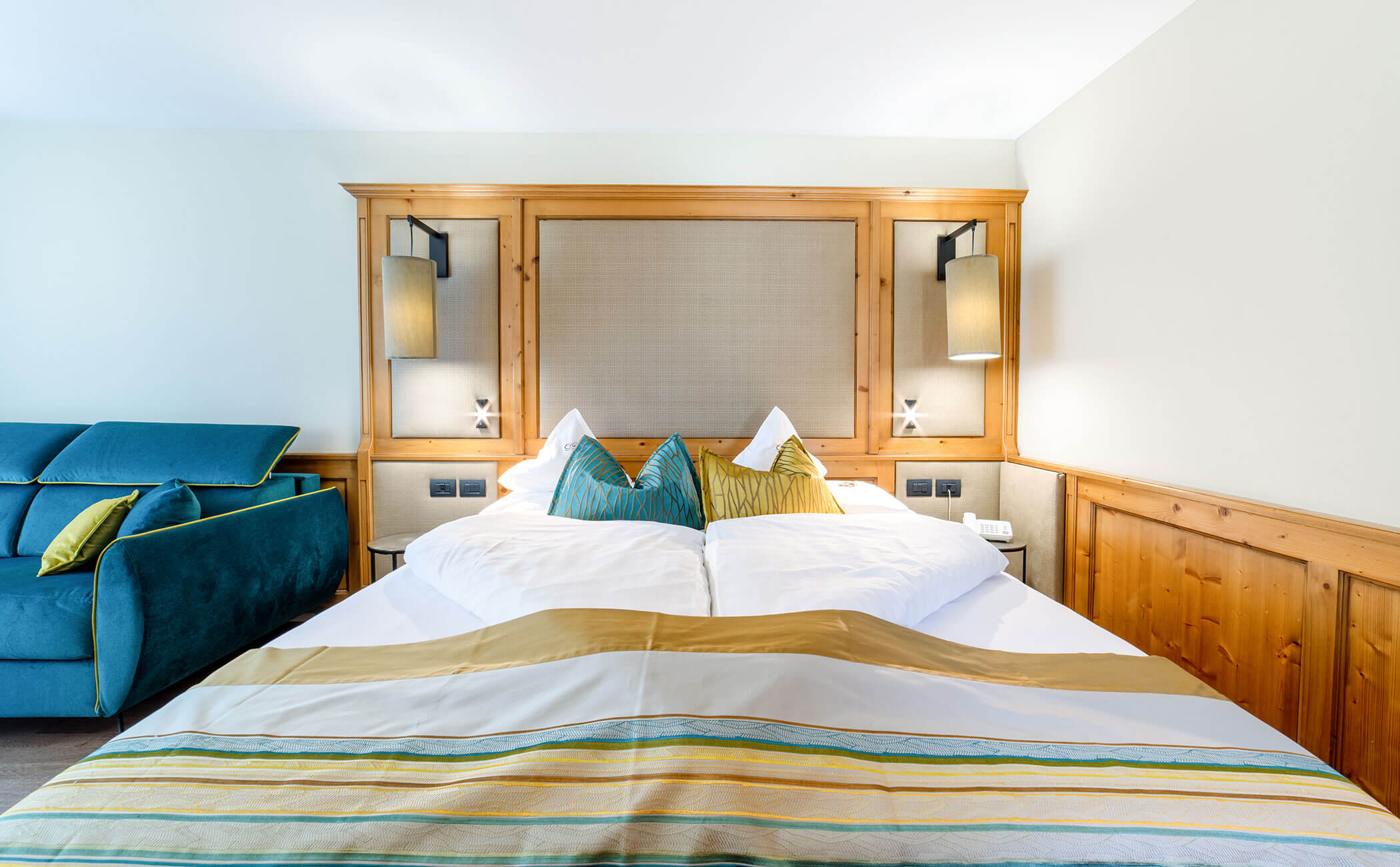 Letto matrimoniale con cuscini gialli e blu nella camera Latemar Superior - Vitalhotel Erica