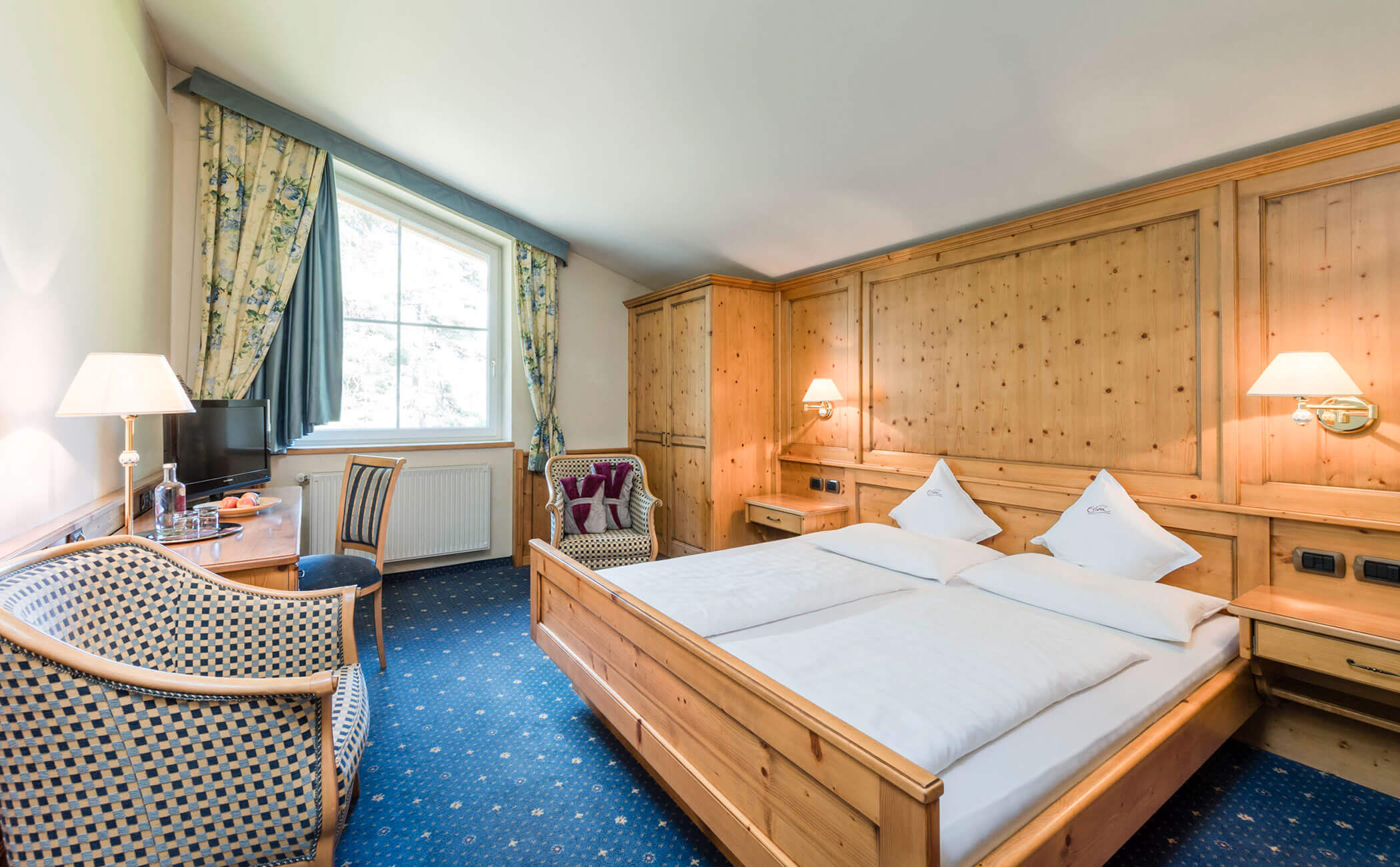 Letto matrimoniale e tende blu-verdi nella camera doppia Schlern - Vitalhotel Erica