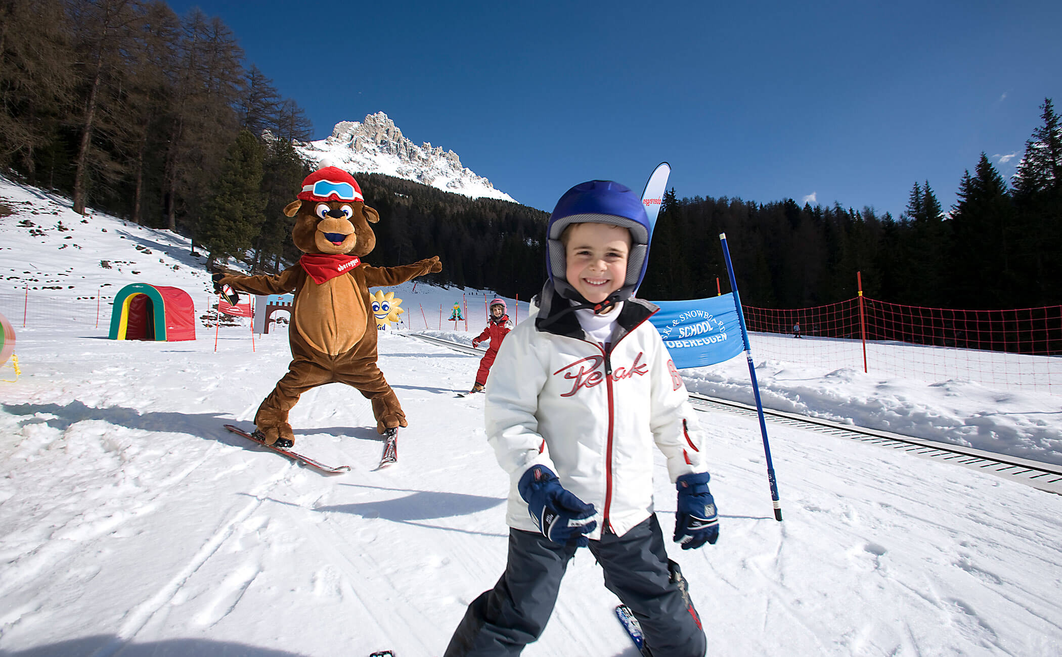 Un bambino e la mascotte sciano a Obereggen - Vitalhotel Erica