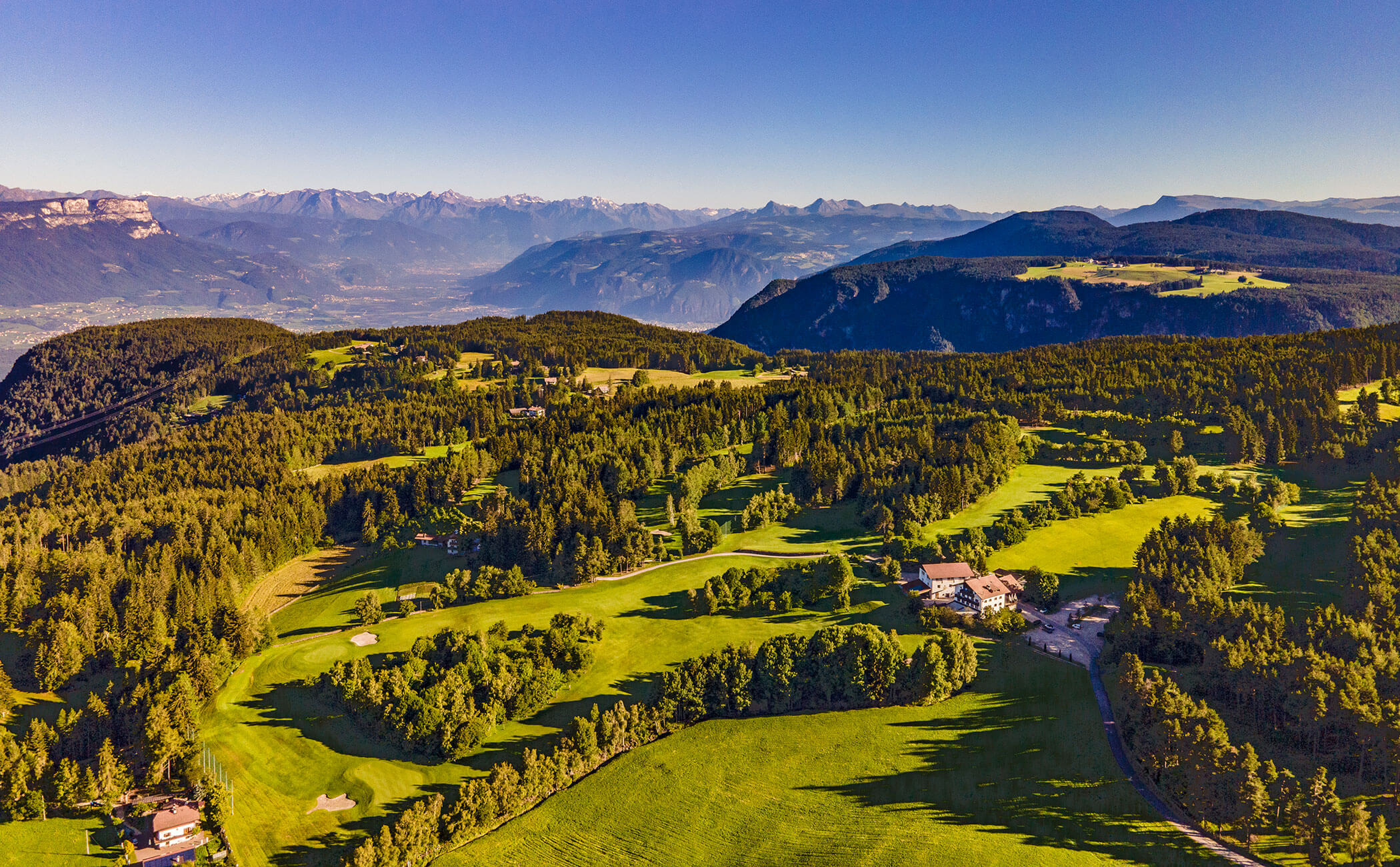 Campi e prati su un altopiano, alcune cime in lontananza - Vitalhotel Erica