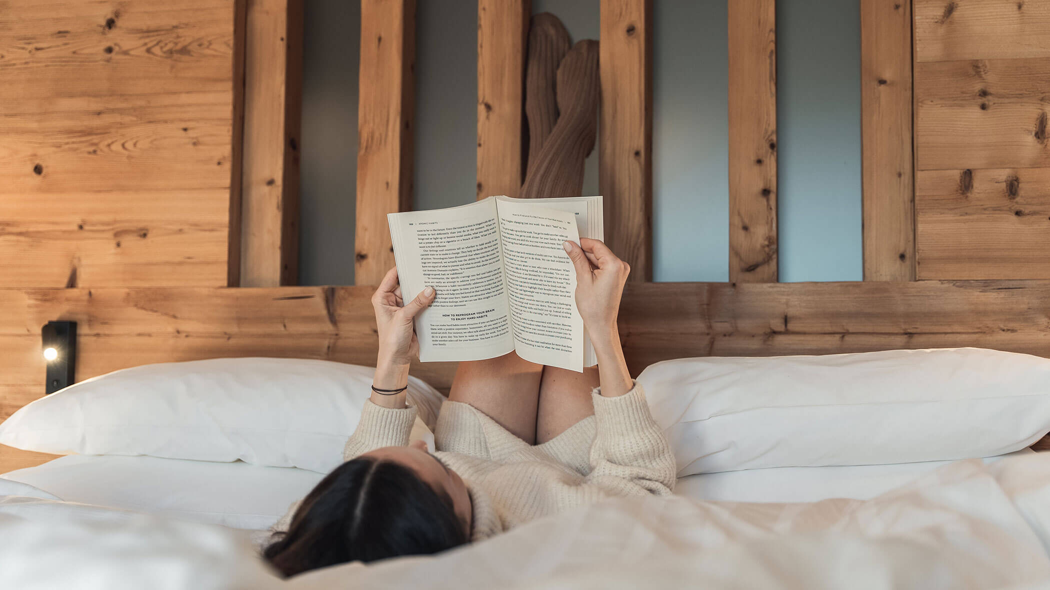 Una donna si sdraia a letto e legge un libro - Vitalhotel Erica
