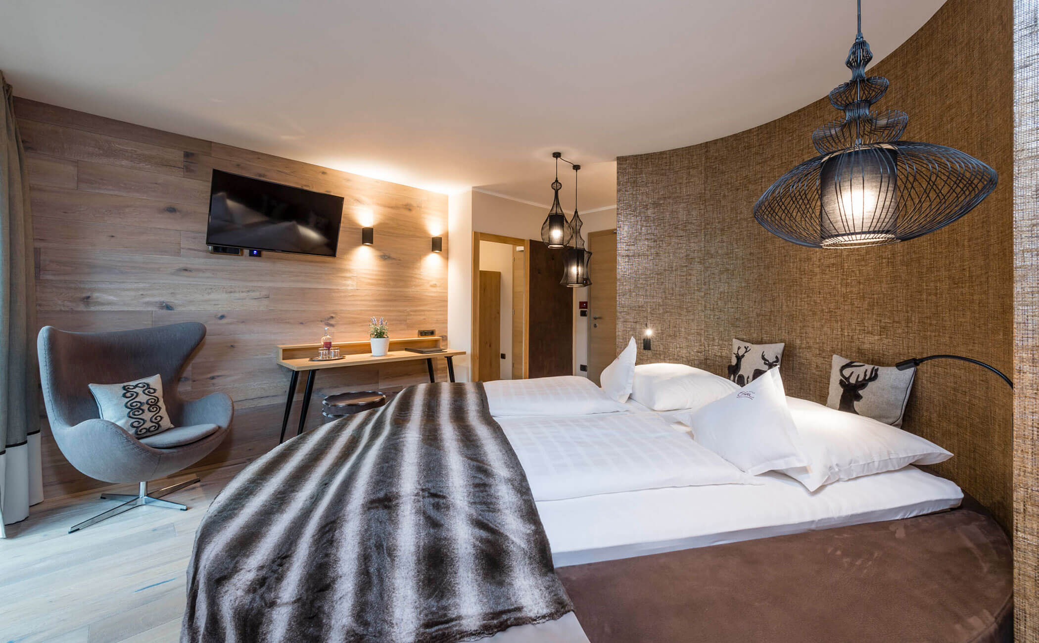 Letto matrimoniale con copriletto e cuscini marroni nella suite Dolomit - Vitalhotel Erica