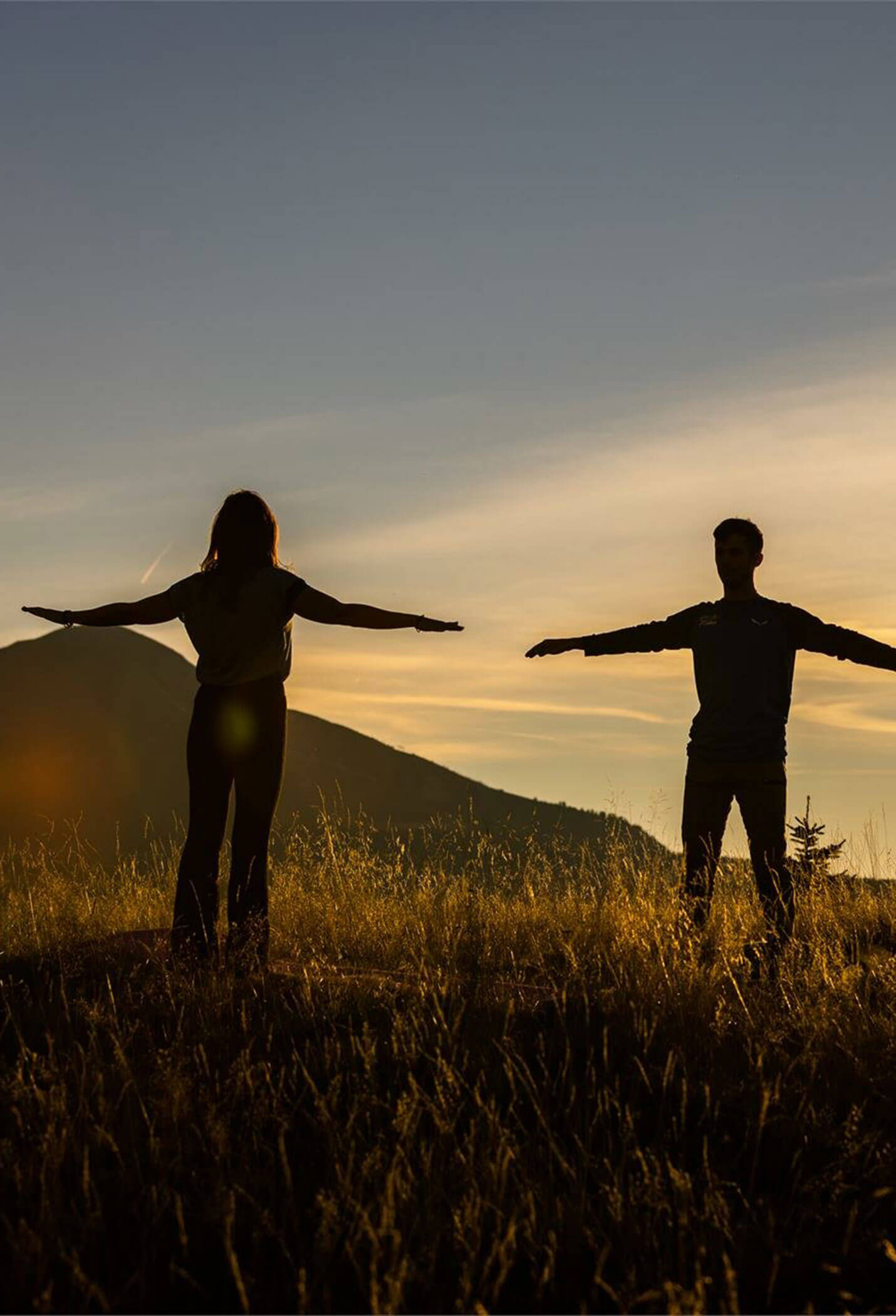 Le sagome di due persone in piedi in un campo che allargano le braccia di lato - Vitalhotel Erica