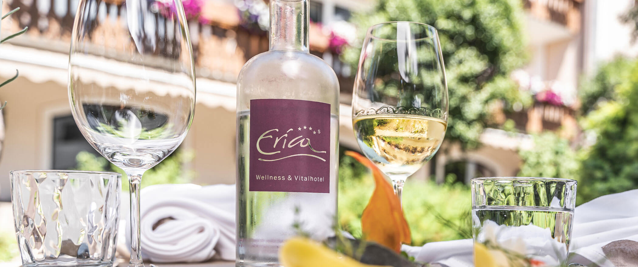 Bottiglia di vetro con acqua e diversi bicchieri su un tavolo all'aperto - Vitalhotel Erica