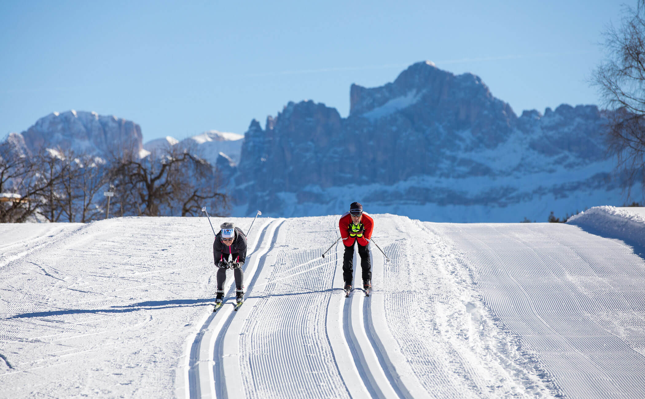 Zwei Langläufer auf der Loipe, dahinter die Dolomiten - Vitalhotel Erica