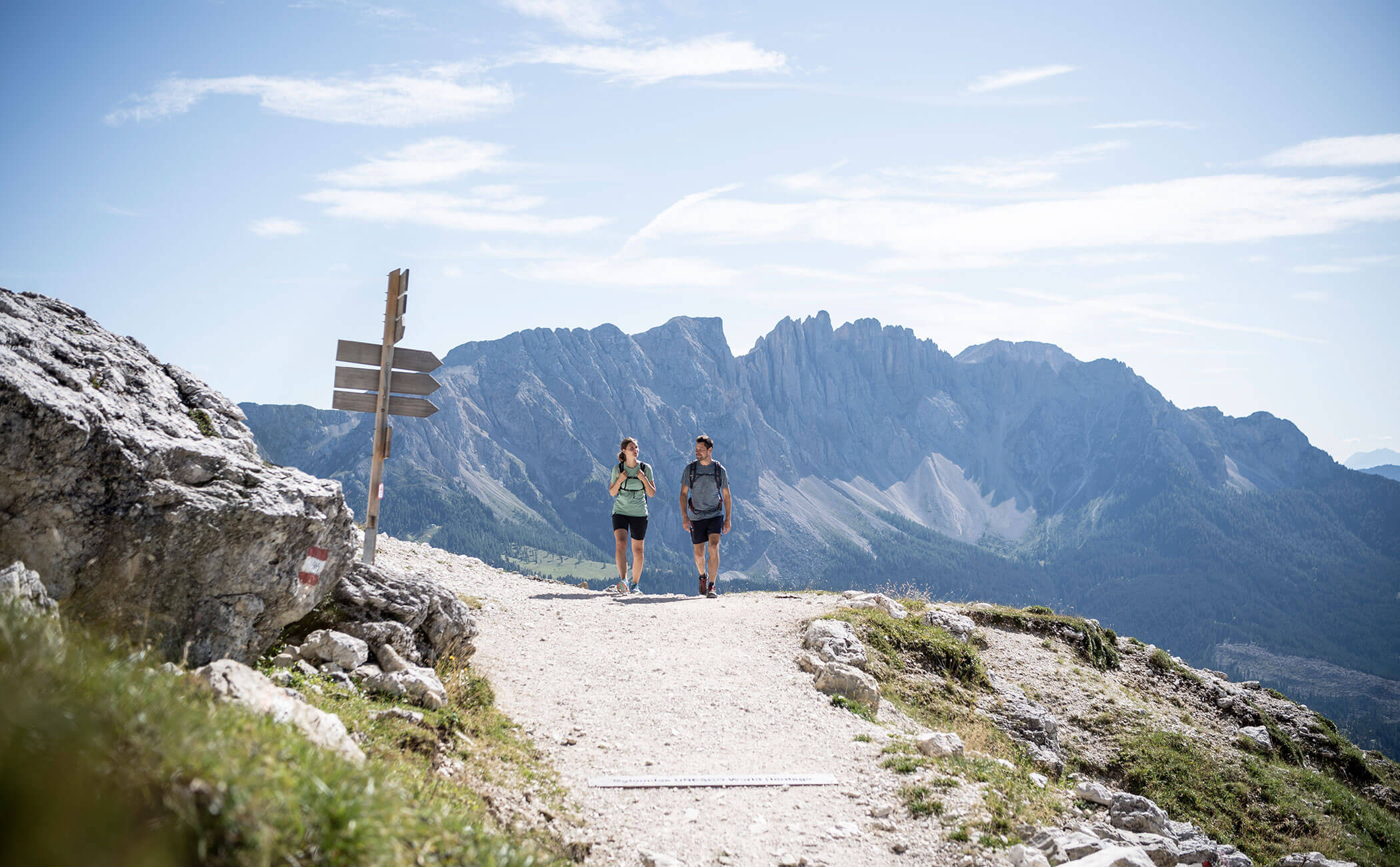 Zwei Wanderer unterwegs in den Dolomiten - daneben ein Wegweiser - Vitalhotel Erica