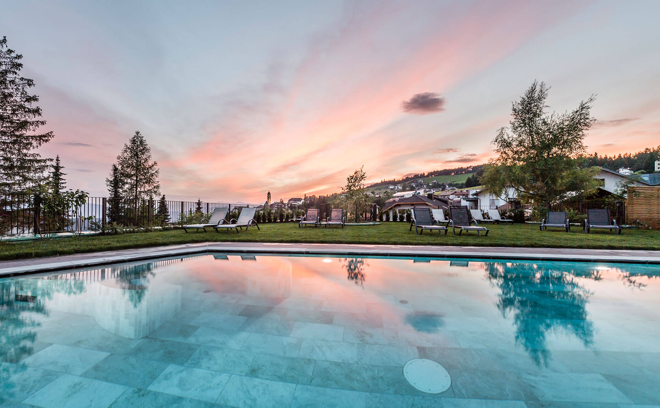 Piscina esterna in estate, con il tramonto alle spalle - Vitalhotel Erica