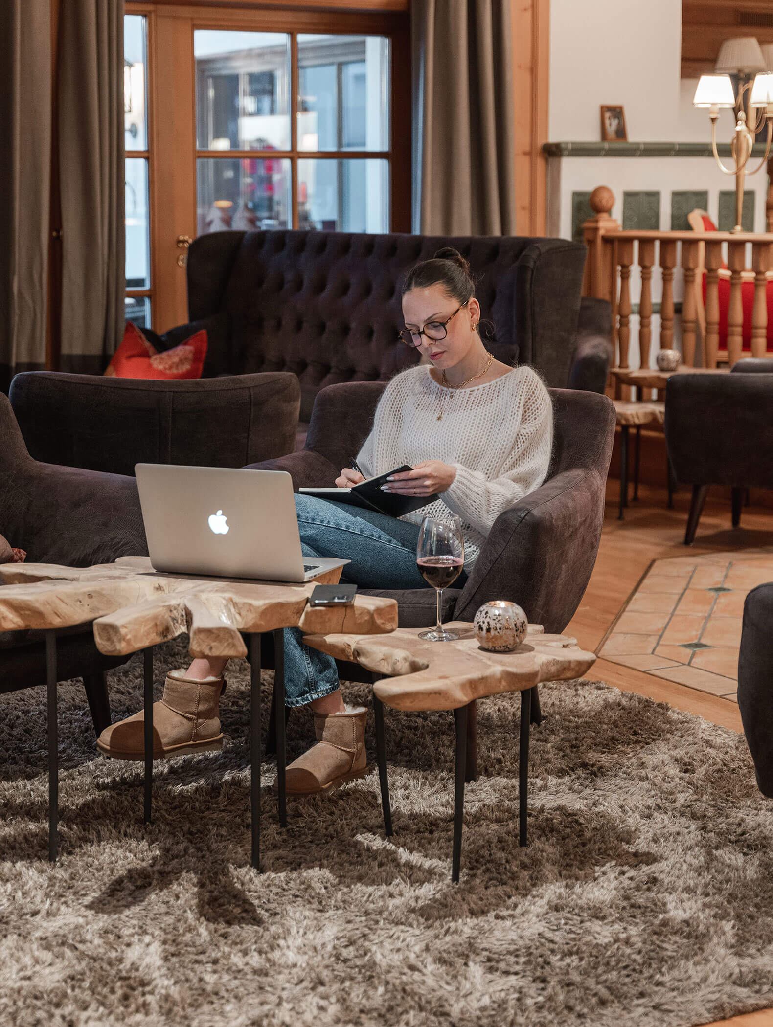 Una donna siede con un bicchiere di vino e un computer portatile nell'area bar e lavora - Vitalhotel Erica