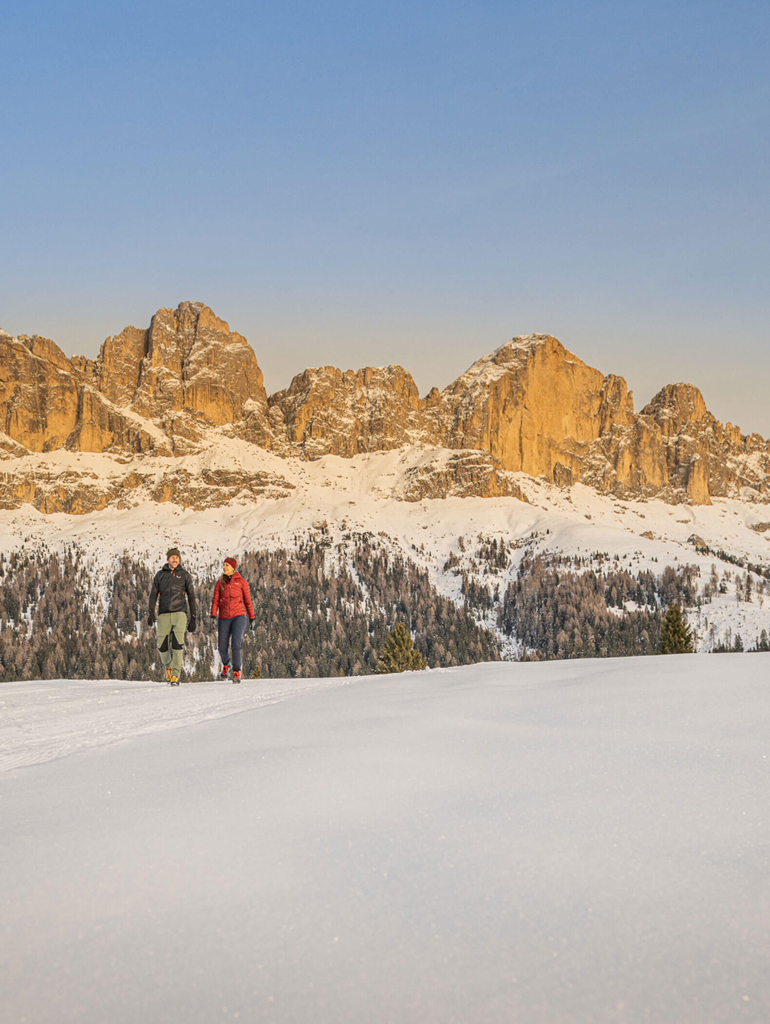 Due escursionisti su un sentiero innevato, con lo sfondo delle Dolomiti alle spalle - Vitalhotel Erica