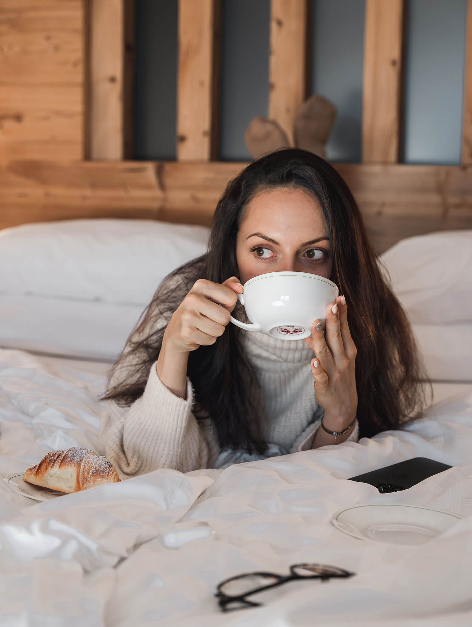 Eine Frau liegt im Bett und trinkt eine Tasse Tee - Vitalhotel Erica