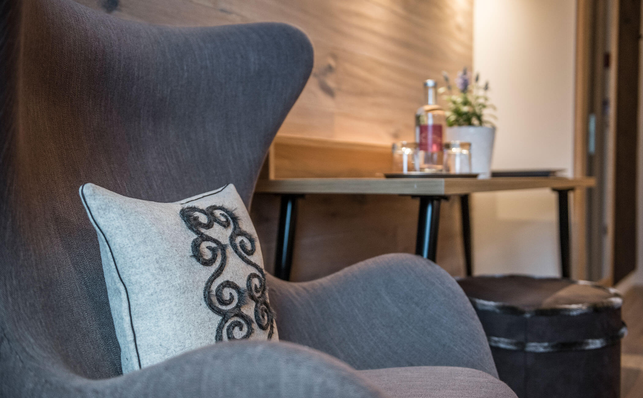 Poltrona grigia con cuscino grigio chiaro nella Suite Dolomit - Vitalhotel Erica