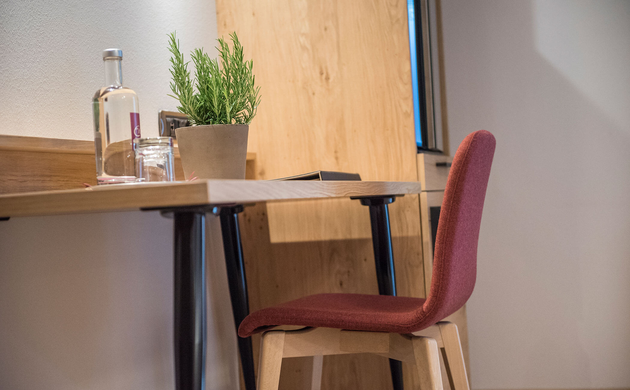Scrivania con rosmarino e sedia rossa nella Suite Dolomit - Vitalhotel Erica