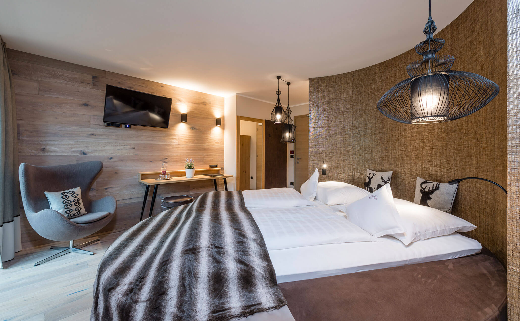 Letto matrimoniale con copriletto e cuscini marroni nella Suite Dolomit - Vitalhotel Erica