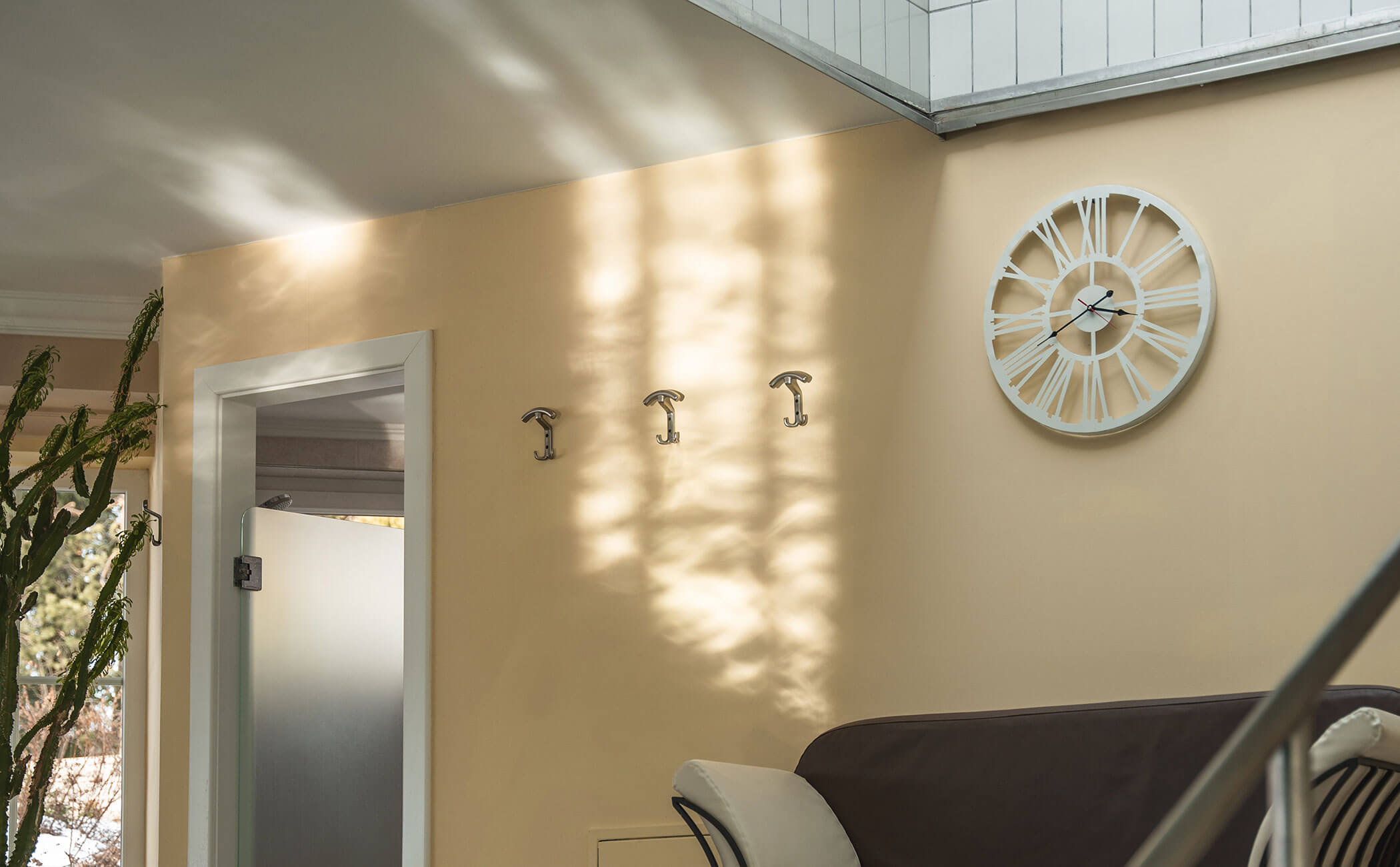 Parete color crema con orologio e appendiabiti bianchi - Vitalhotel Erica