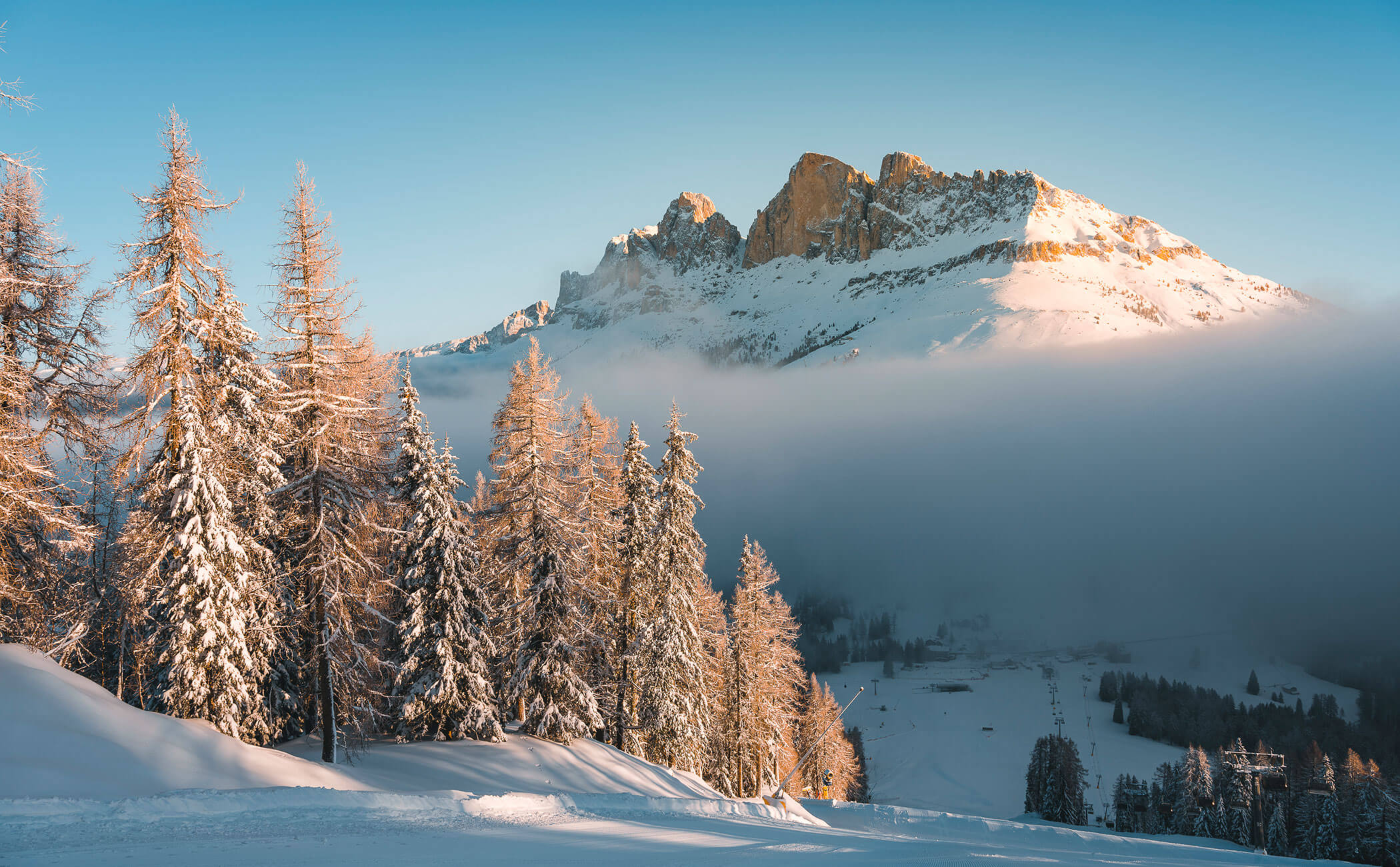 La pista da sci ben preparata, gli alberi innevati e le cime delle montagne dall'altra parte della valle - Vitalhotel Erica