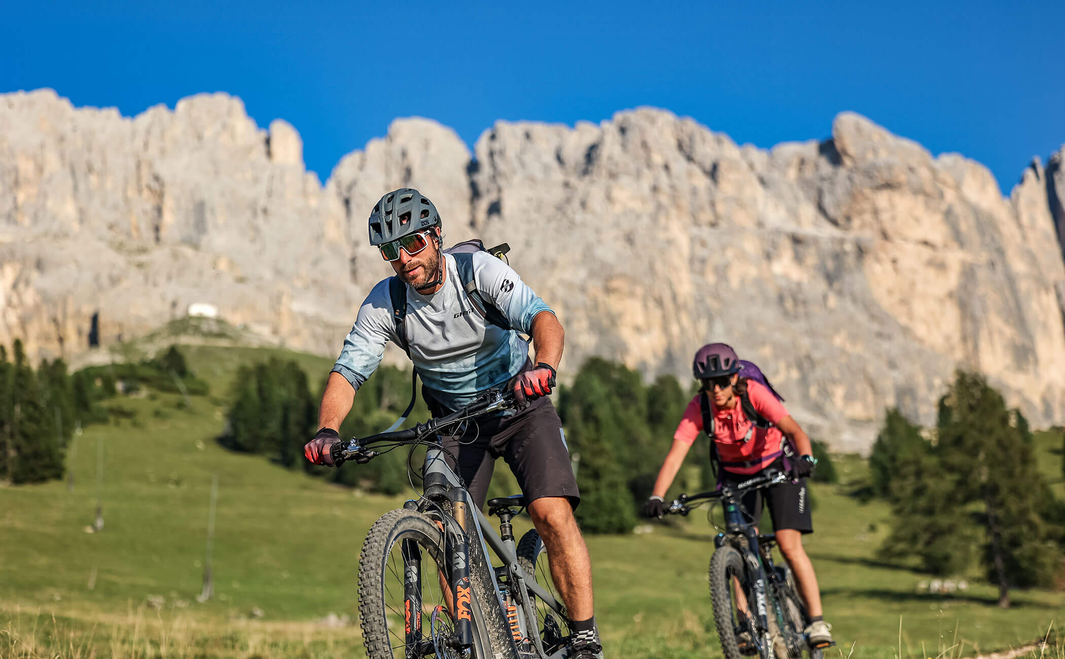 Una coppia in discesa con la mountain bike, alle spalle le Dolomiti - Vitalhotel Erica